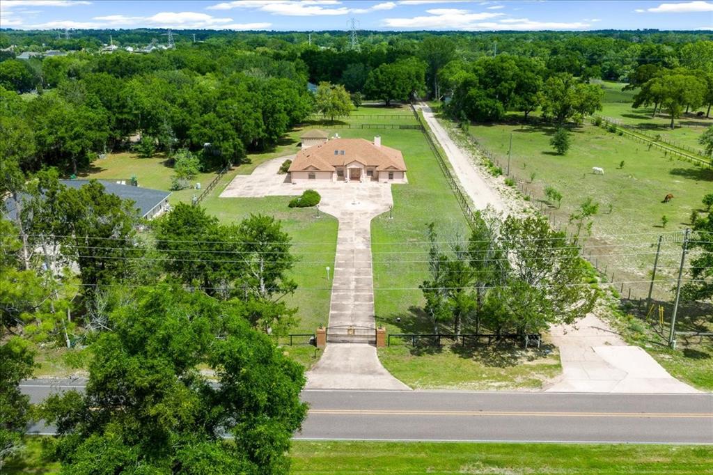 An aerial view shows a single-story house with a long driveway behind a gated entrance — 5085 SE 38TH STREET, OCALA, FL