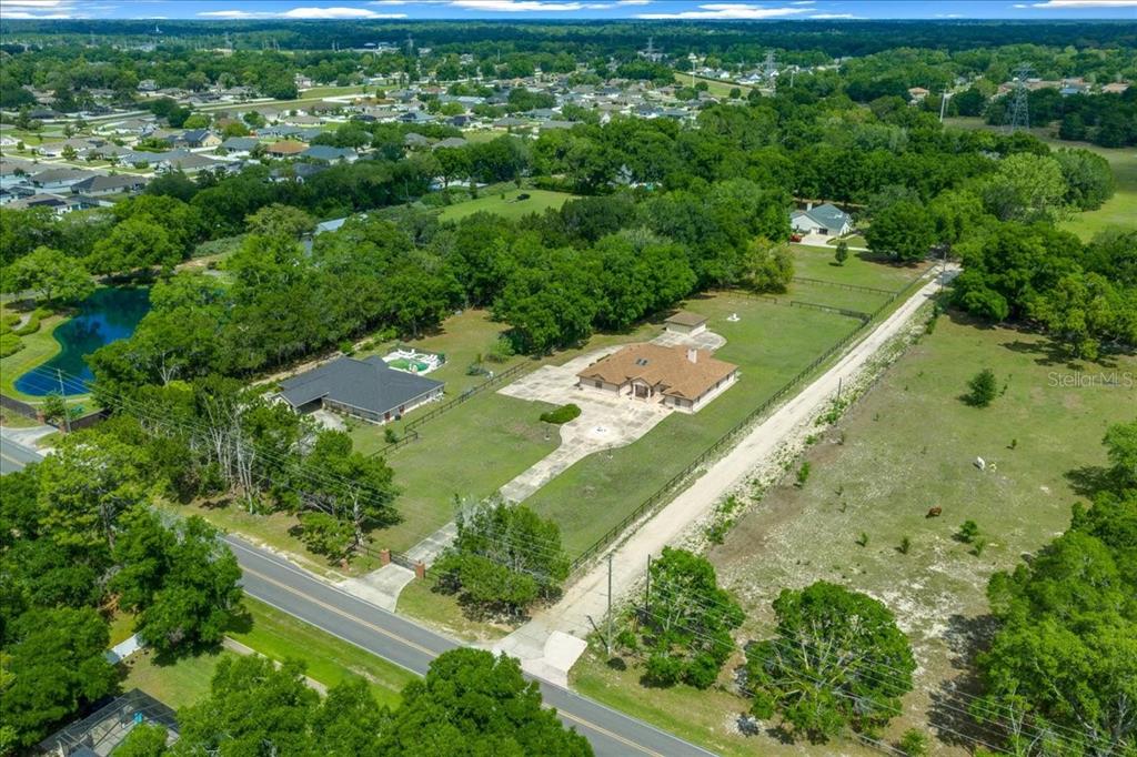 An aerial view shows two houses on a large, grassy lot with trees and fencing — 5085 SE 38TH STREET, OCALA, FL