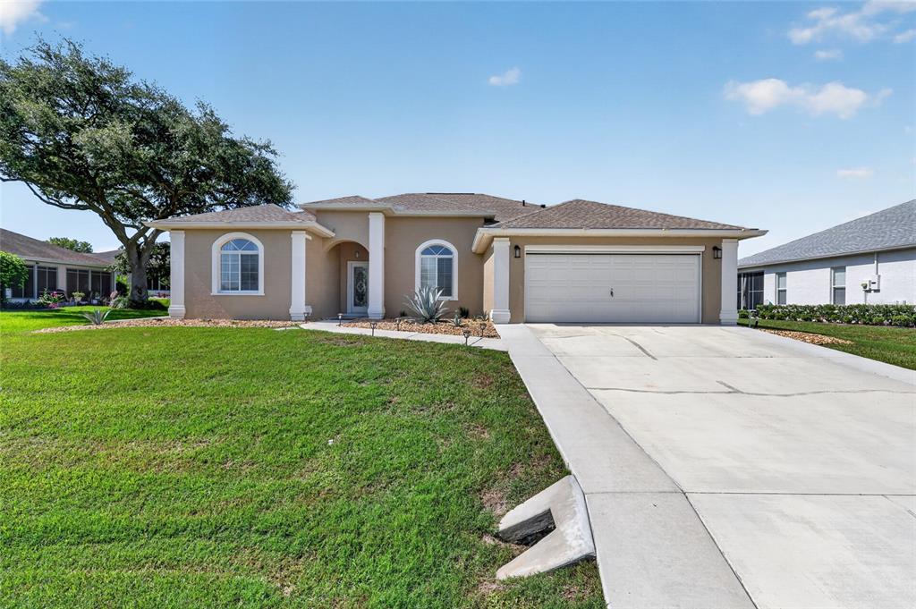 A tan single-story house with a two-car garage and a large front lawn — 5770 N NW 21ST STREET, OCALA, FL