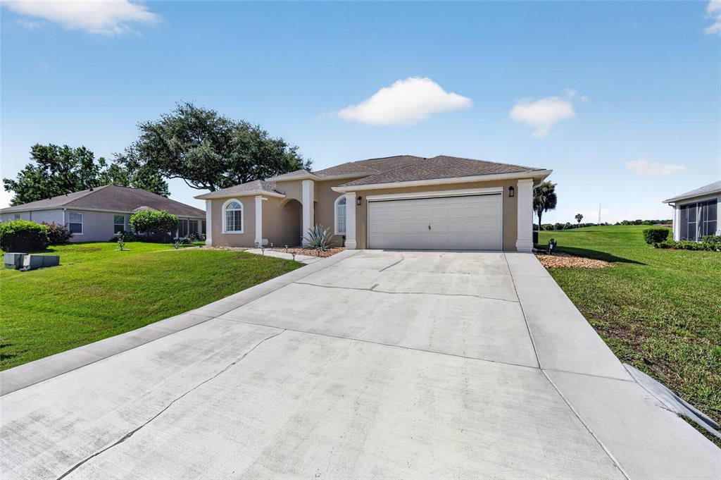 A single-story house with a beige exterior, a two-car garage, and a concrete driveway — 5770 N NW 21ST STREET, OCALA, FL
