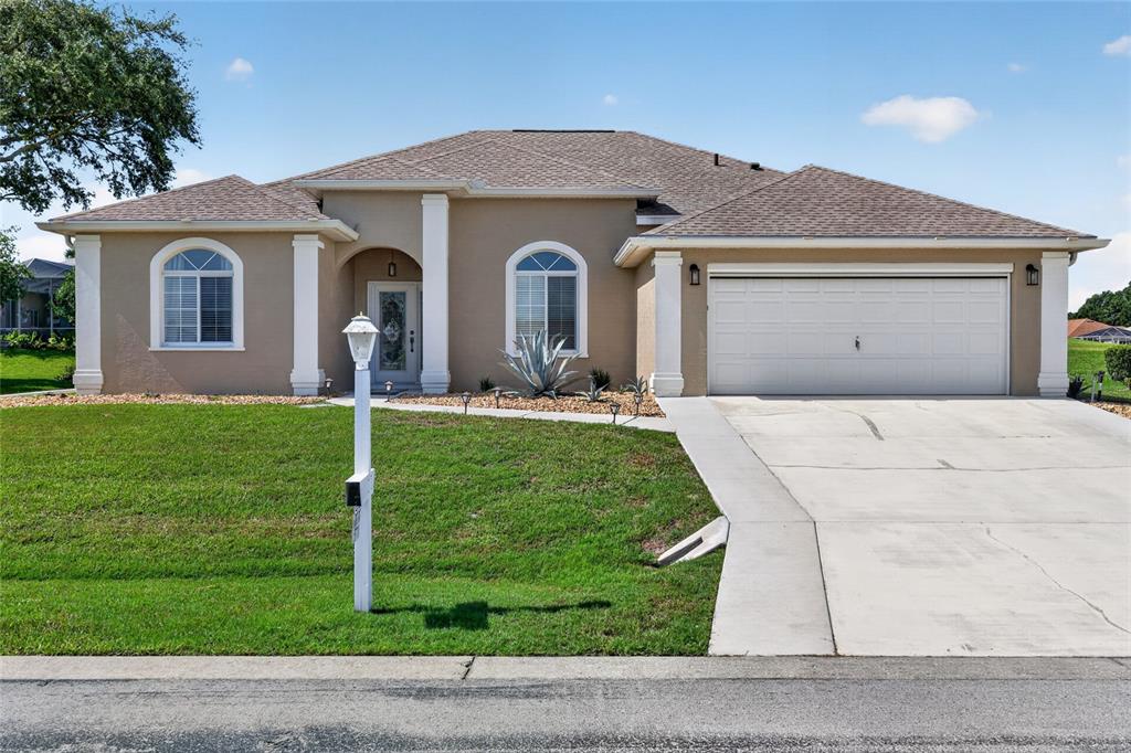 A single-story house with a tan stucco exterior, arched windows, and a two-car garage — 5770 N NW 21ST STREET, OCALA, FL