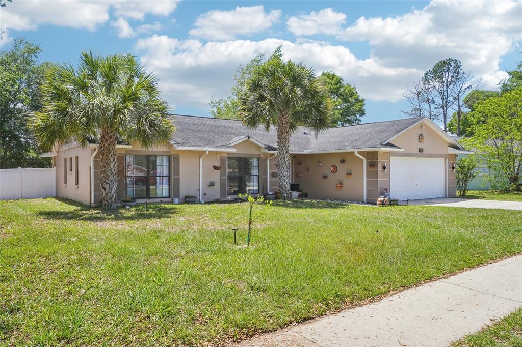 A single-story house with a beige stucco exterior, a two-car garage, and two palm trees — 236 MARION OAKS LANE, OCALA, FL