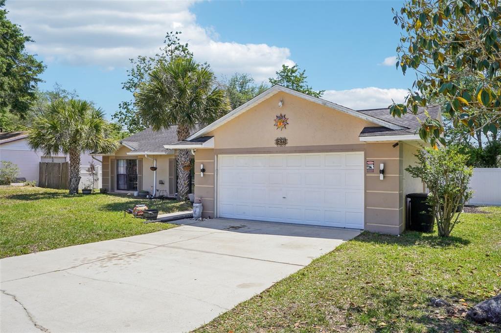 A single-story house with a beige stucco exterior, a two-car garage, and a concrete driveway — 236 MARION OAKS LANE, OCALA, FL