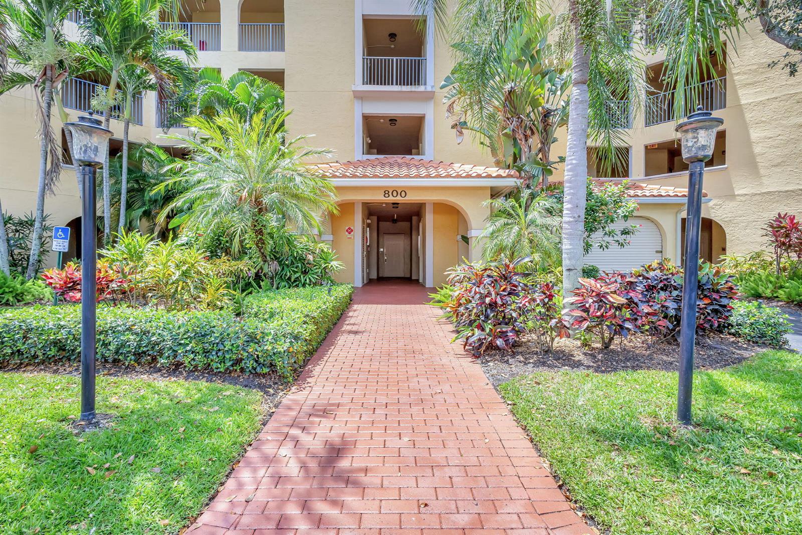 A brick walkway leads to the entrance of a multi-story building marked with number 800 — 800 Uno Lago Drive # 302, Juno Beach FL 33408, JUNO BEACH, FL
