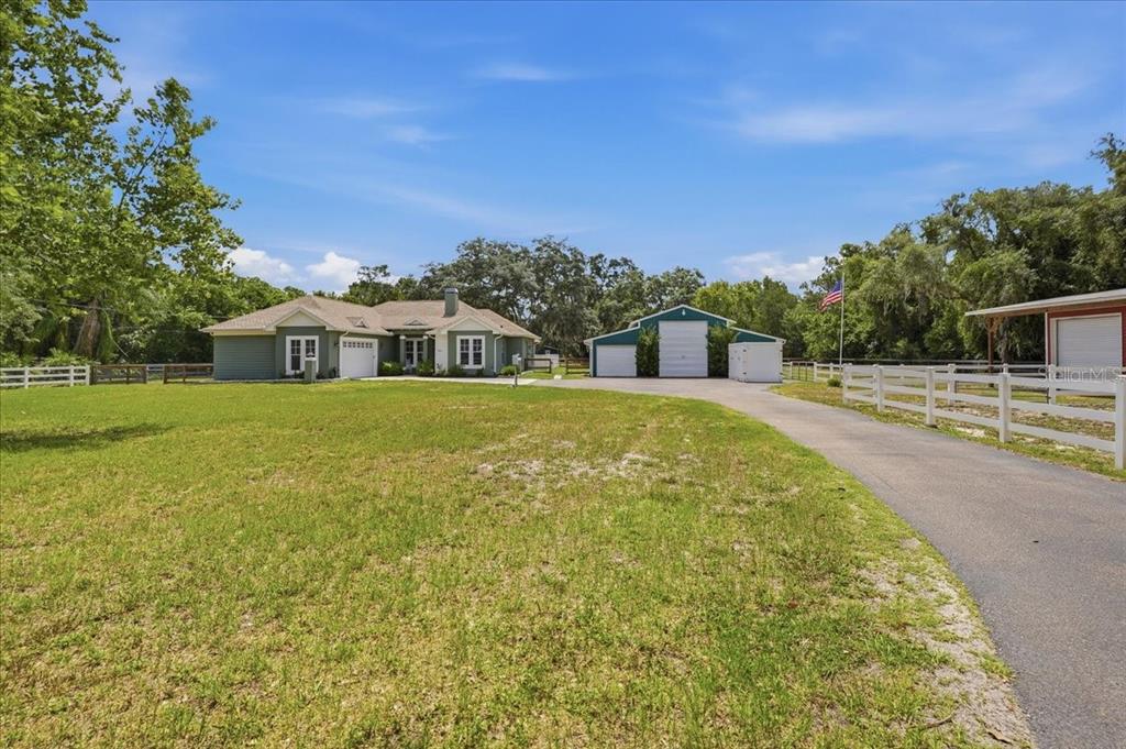 A single-story house and a detached garage sit on a large, grassy, fenced lot — 7014 JONES ROAD, ODESSA, FL