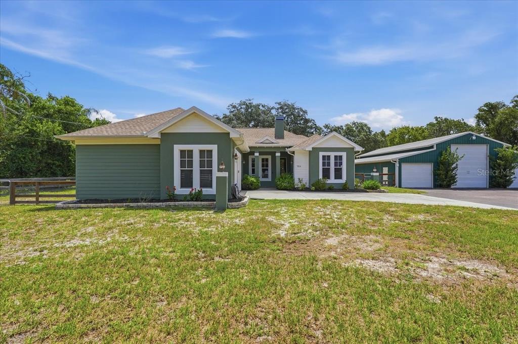 A green single-story house with a white-trimmed exterior and an adjacent detached garage — 7014 JONES ROAD, ODESSA, FL