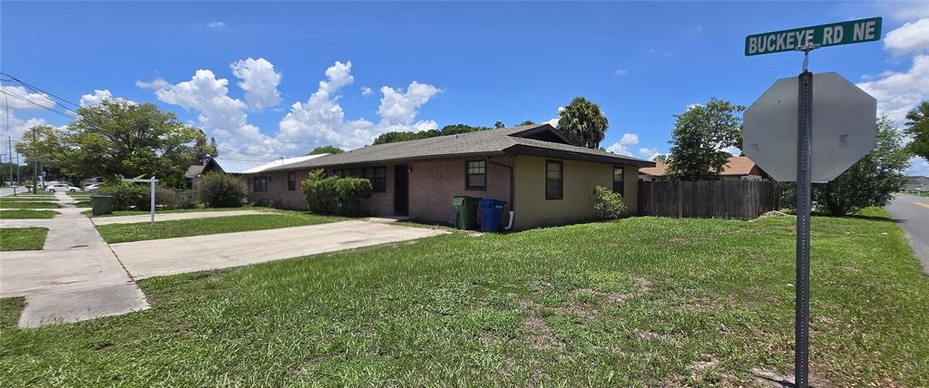 A single-story brick house with a concrete driveway sits on a corner lot — 2021 BUCKEYE ROAD NE, WINTER HAVEN, FL