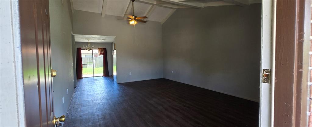 A view from a doorway into a living room with dark flooring and vaulted ceilings — 2021 BUCKEYE ROAD NE, WINTER HAVEN, FL