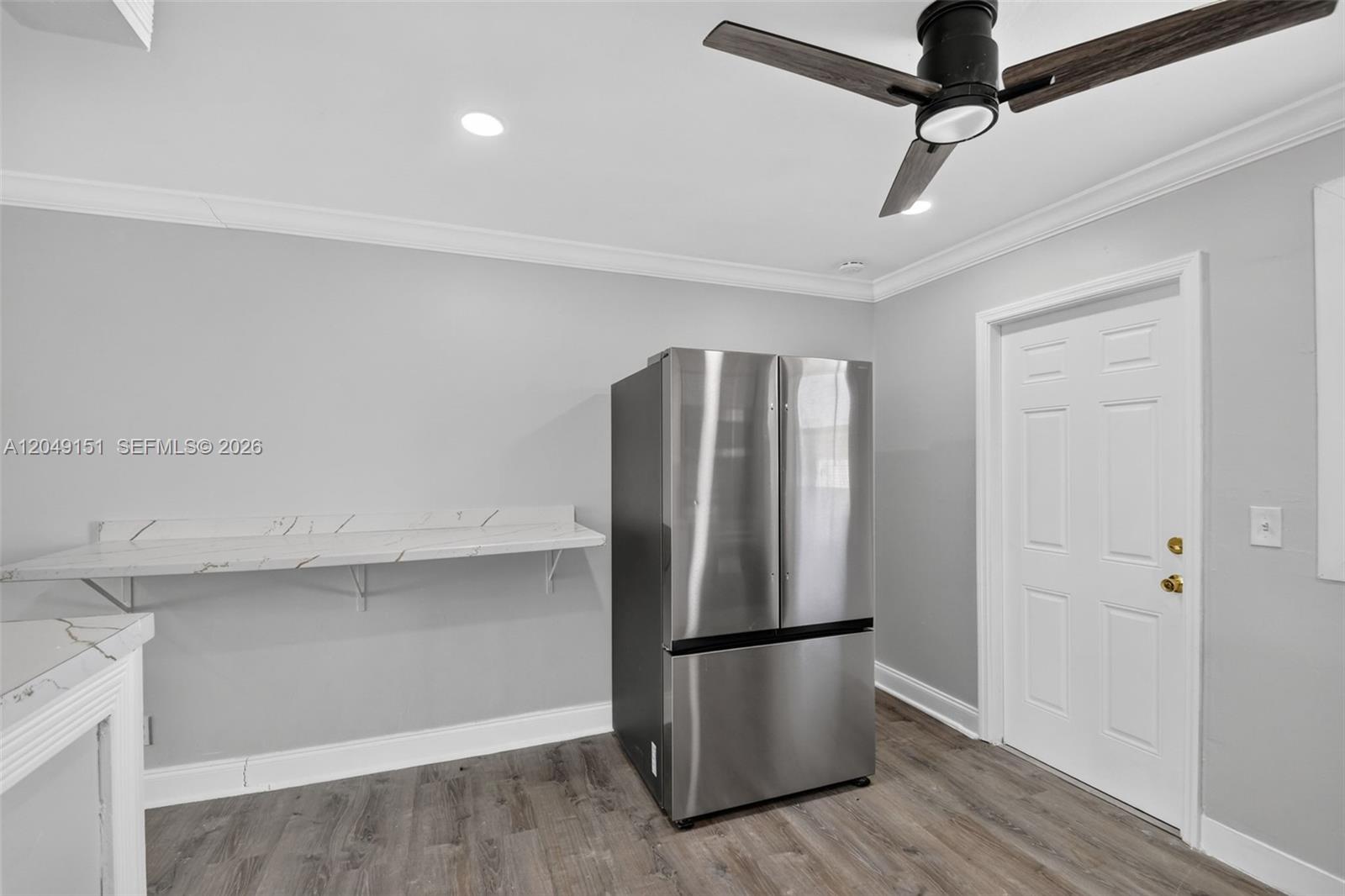 A kitchen area features a stainless steel refrigerator, a marble-look counter, and wood-style flooring — 824 Bayberry Dr, Lake Park FL 33403, LAKE PARK, FL