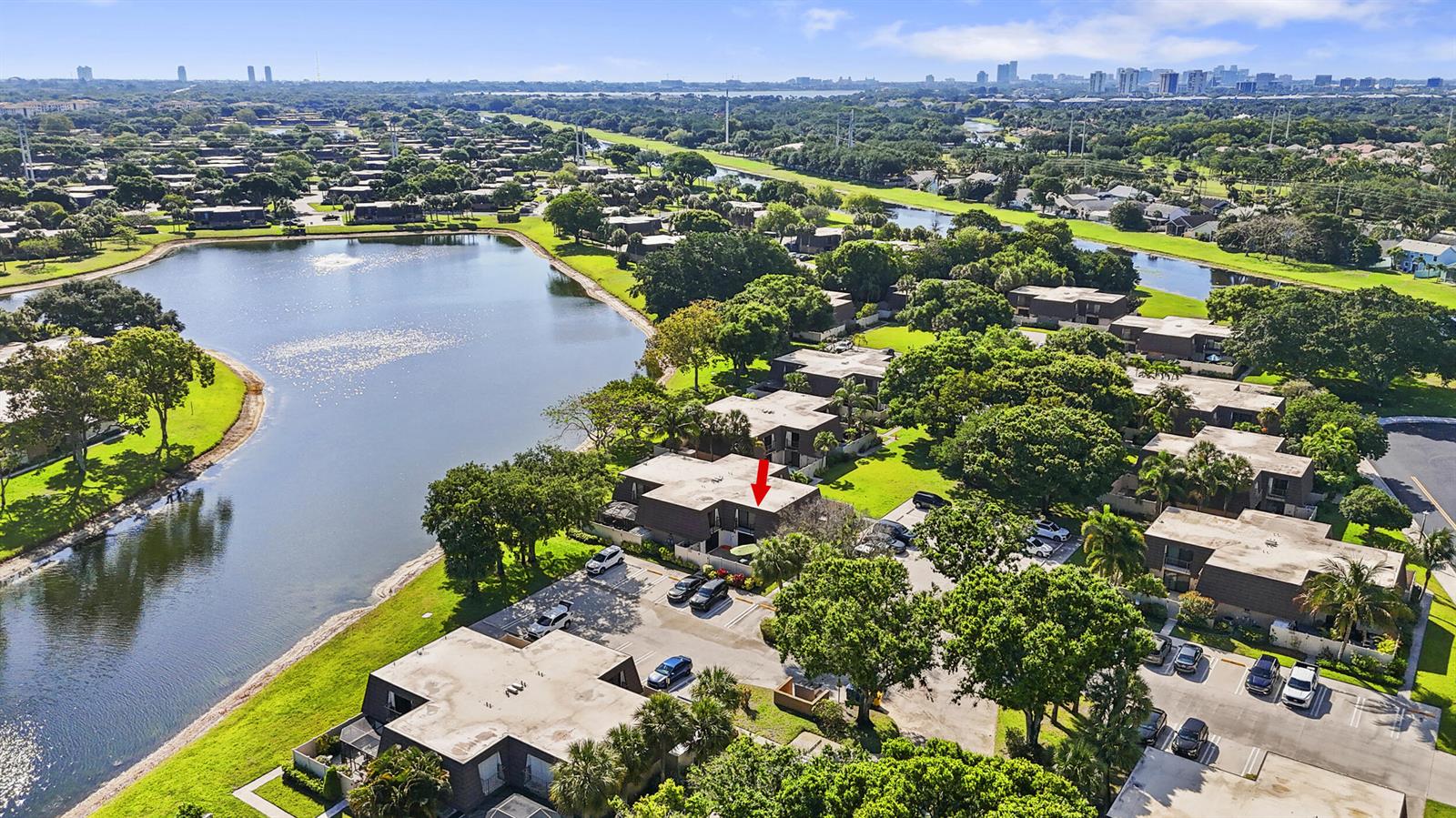 An aerial view shows a multi-unit residential complex situated beside a large lake — 7813 78th Way, West Palm Beach FL 33407, WEST PALM BEACH, FL