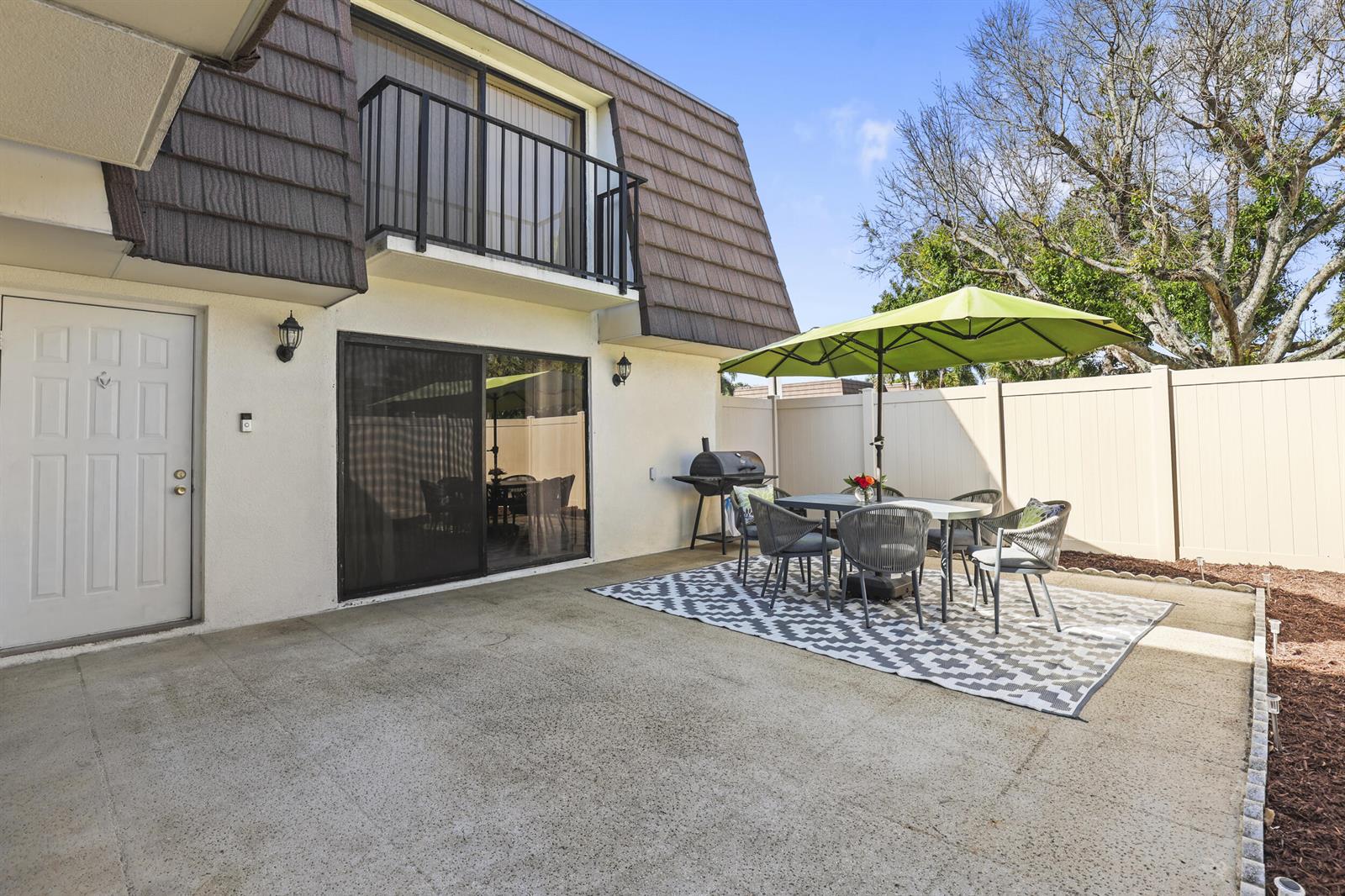 A patio area features a dining set with a green umbrella and a charcoal grill — 7813 78th Way, West Palm Beach FL 33407, WEST PALM BEACH, FL