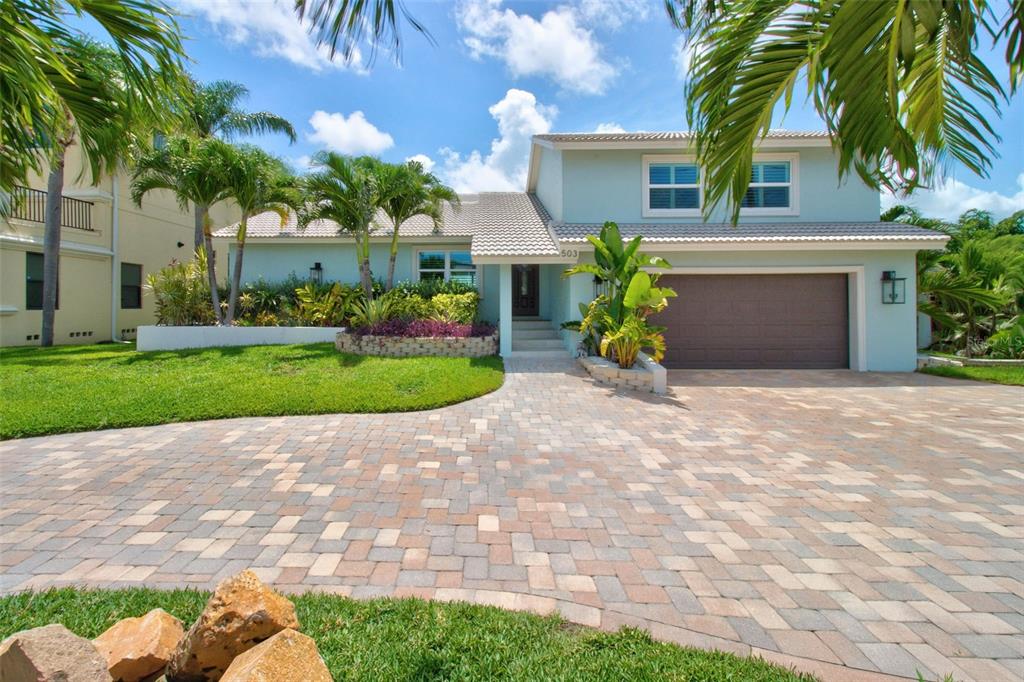 A light blue two-story house features a paver driveway, a front lawn, and palm trees — 503 JOHNS PASS AVENUE, MADEIRA BEACH, FL