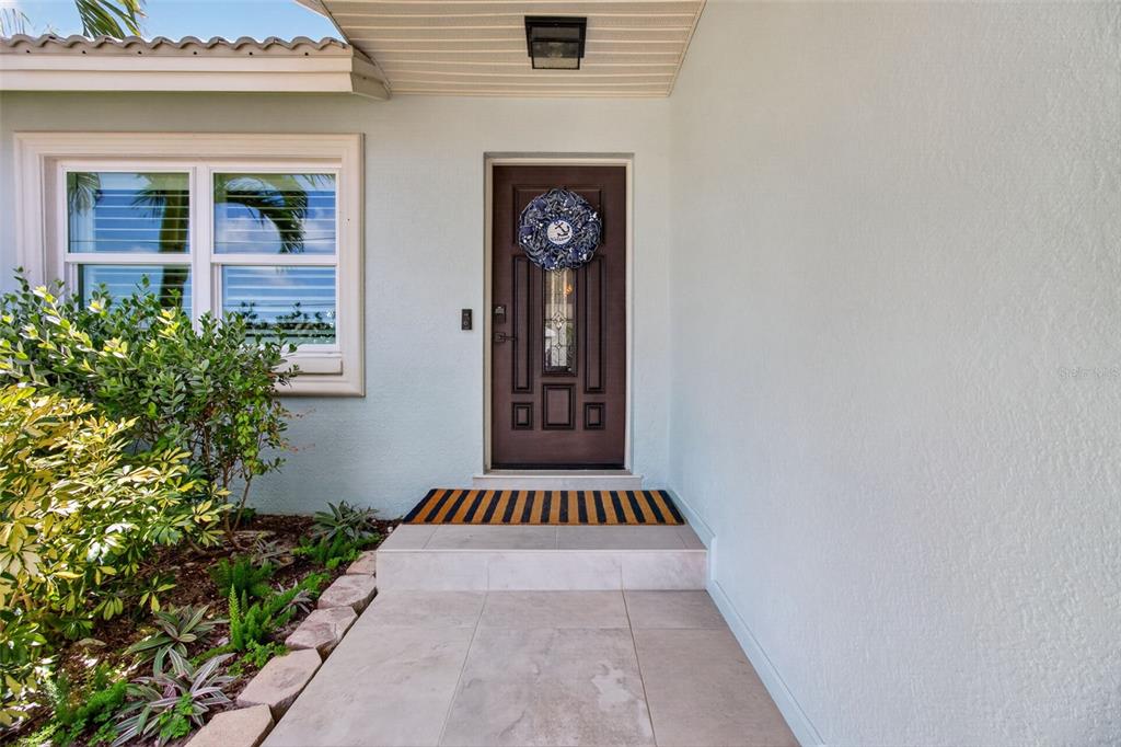 A front entryway features a brown door with a wreath, tiled steps, and landscaping — 503 JOHNS PASS AVENUE, MADEIRA BEACH, FL