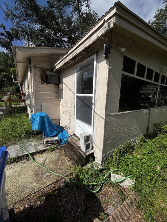The exterior of a house features a screened porch, a side door, and a yard — 7221 WESTINGHOUSE AVENUE, TAMPA, FL