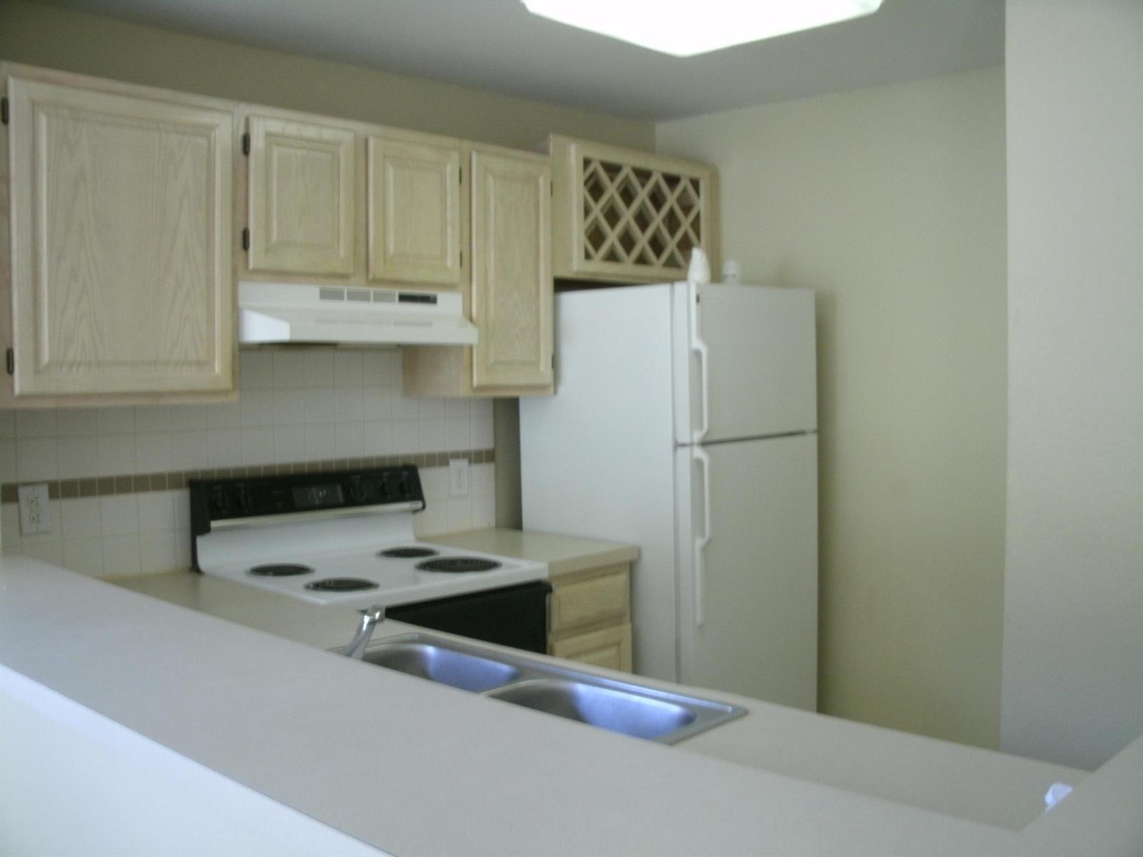 A kitchen features light wood cabinets, white appliances, a double sink, and a breakfast bar — 1780 Palm Cove Boulevard # 302, Delray Beach FL 33445, DELRAY BEACH, FL