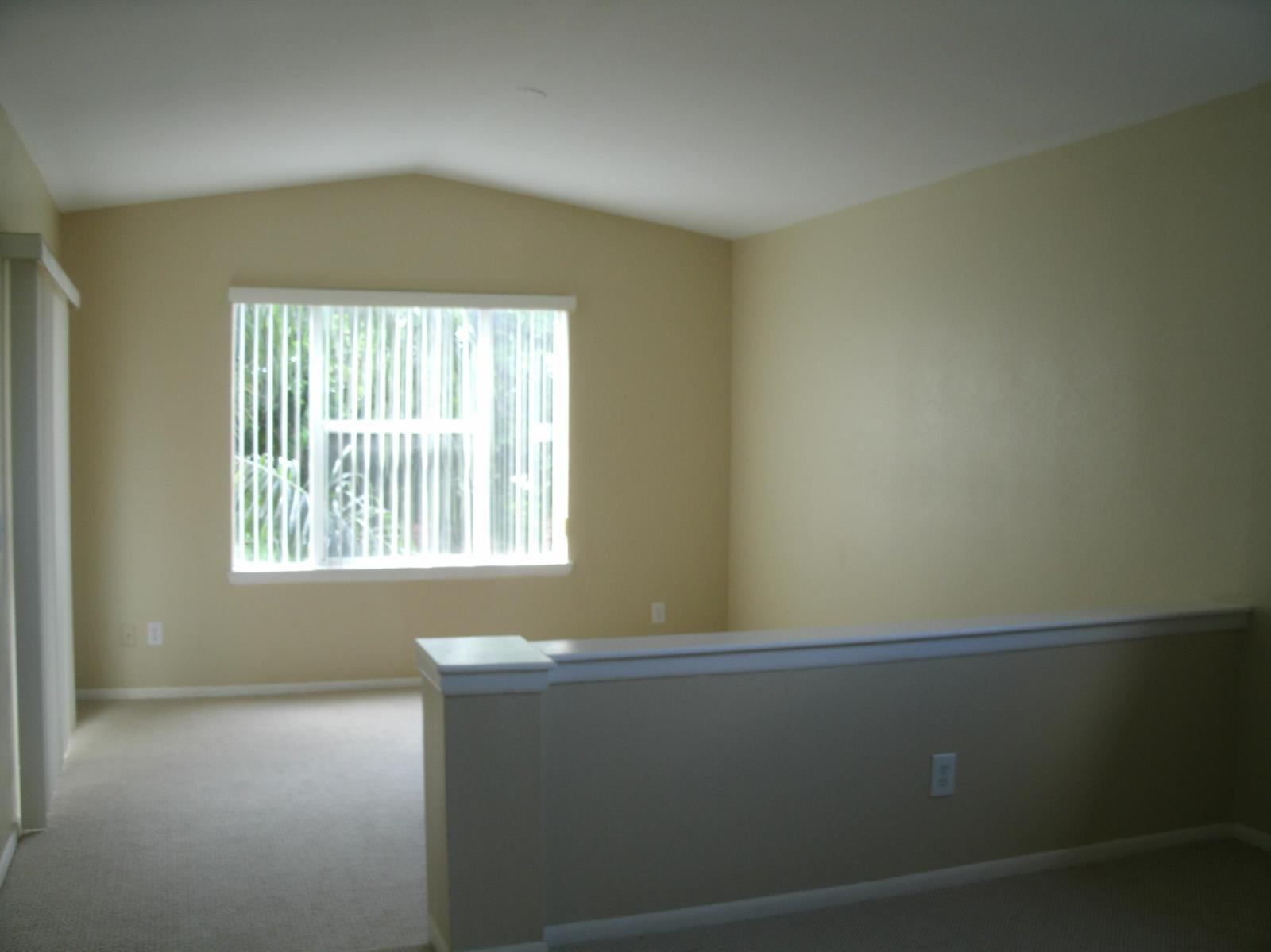 An empty room with beige walls, carpeted flooring, a vaulted ceiling, and a half wall — 1780 Palm Cove Boulevard # 302, Delray Beach FL 33445, DELRAY BEACH, FL