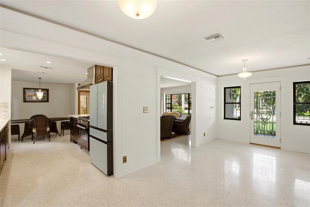 A bright, open-concept room with white walls, terrazzo flooring, and views into the kitchen area — 2706 RHODE ISLAND AVENUE, FORT MYERS, FL