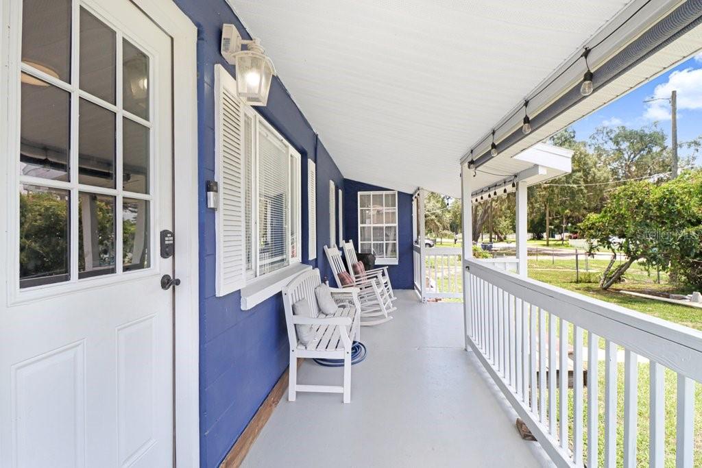 A blue-sided house features a covered porch with white railings, rocking chairs, and string lights — 11110 HACKNEY DRIVE, RIVERVIEW, FL