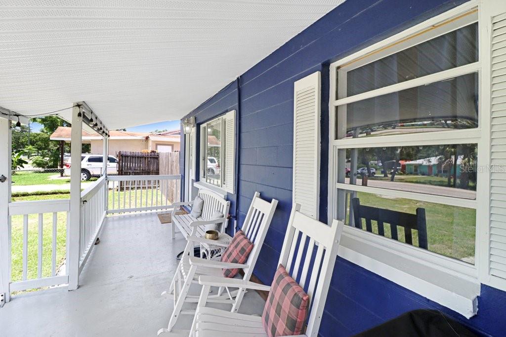A covered porch features blue exterior walls, white railings, and two white rocking chairs — 11110 HACKNEY DRIVE, RIVERVIEW, FL
