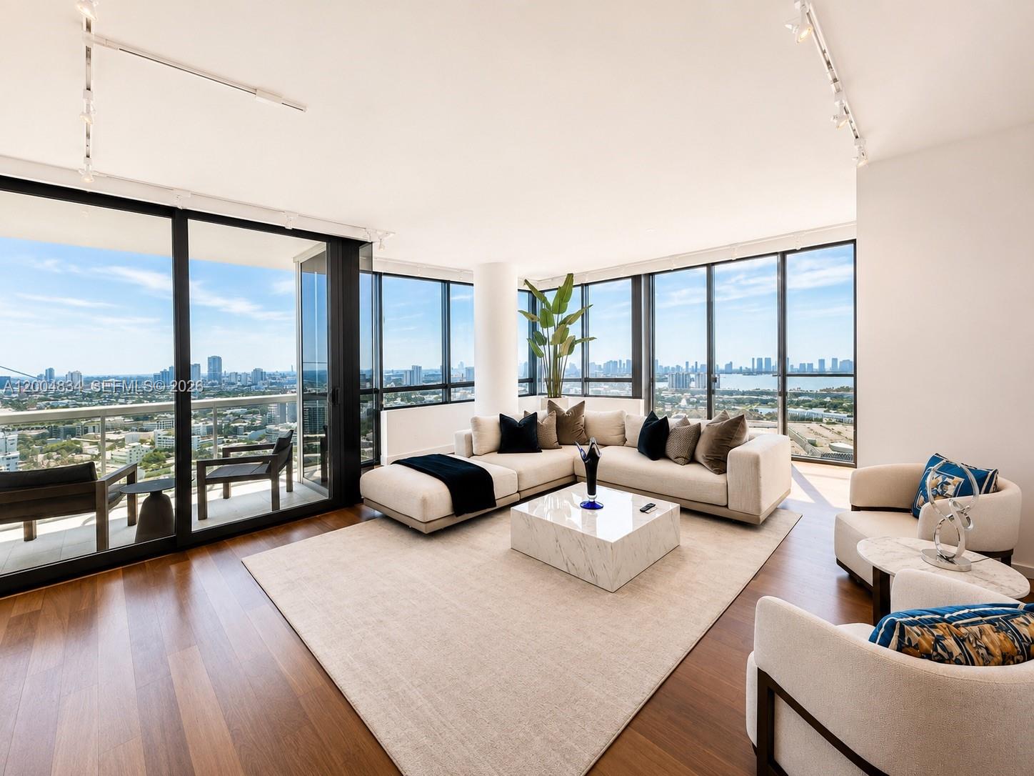 A modern living room features floor-to-ceiling windows, a sectional sofa, and hardwood flooring — 101 20th St # 3501, Miami Beach FL 33139, MIAMI BEACH, FL