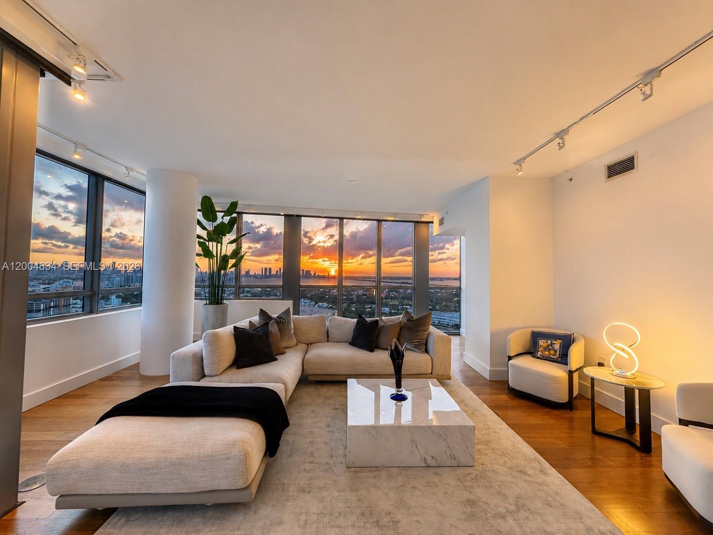 A modern living room features a large sectional sofa, marble coffee table, and floor-to-ceiling windows — 101 20th St # 3501, Miami Beach FL 33139, MIAMI BEACH, FL
