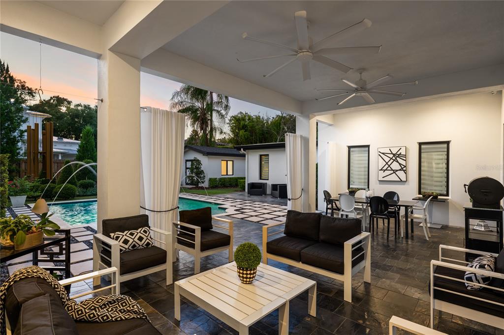 A covered outdoor patio features dark tile flooring, modern furniture, ceiling fans, and a swimming pool — 1581 FOREST AVENUE, WINTER PARK, FL