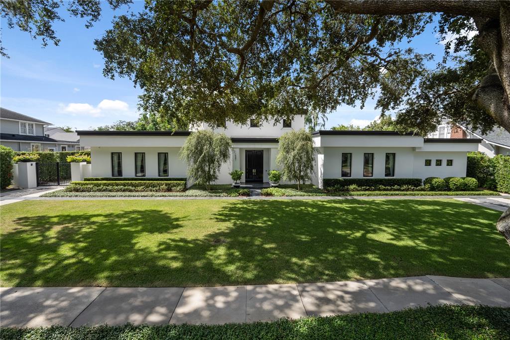 A modern white house with a flat roof and symmetrical windows sits behind a lawn — 1581 FOREST AVENUE, WINTER PARK, FL