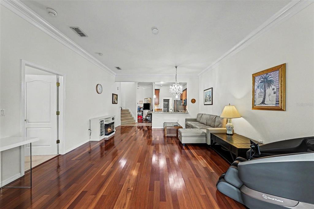 A living room with hardwood floors, a fireplace, a sectional sofa, and a massage chair — 7411 WIMPOLE DRIVE, NEW PORT RICHEY, FL