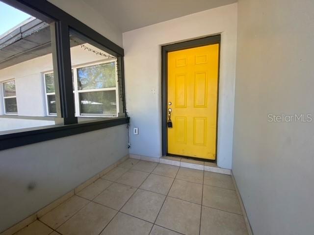 A covered porch features a bright yellow front door and light-colored tiled flooring — 2510 14TH STREET S, ST PETERSBURG, FL