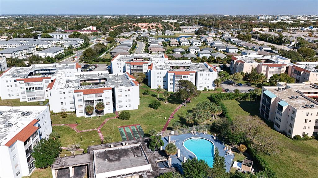 An aerial view shows multiple apartment buildings, a swimming pool, and surrounding green spaces — 2850 SOMERSET DRIVE UNIT 204L, LAUDERDALE LAKES, FL