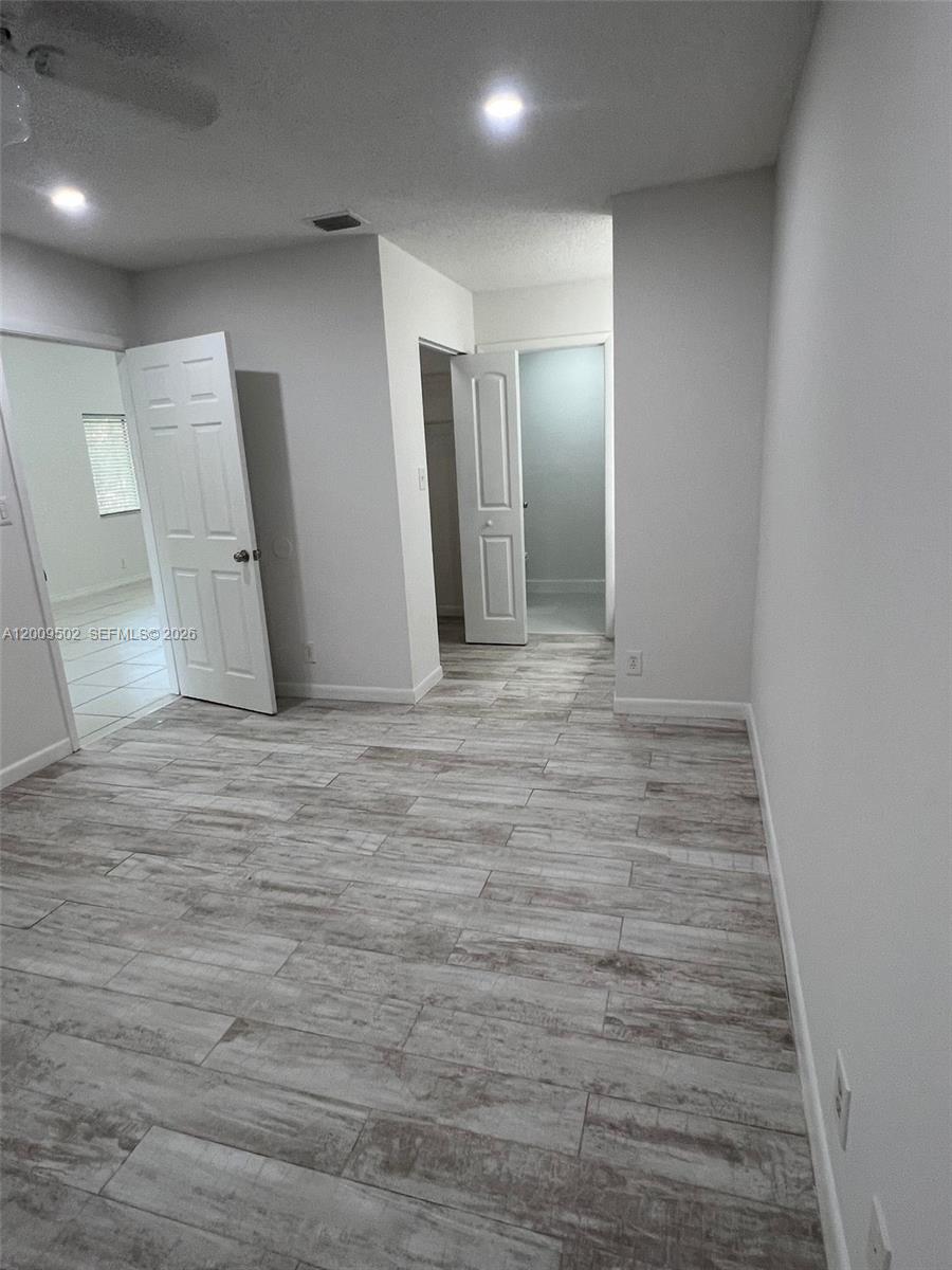 This room features light-colored wood-look tile flooring, white walls, and two open interior doors — 9203 SW 138th Pl # 9203, Miami FL 33186, MIAMI, FL