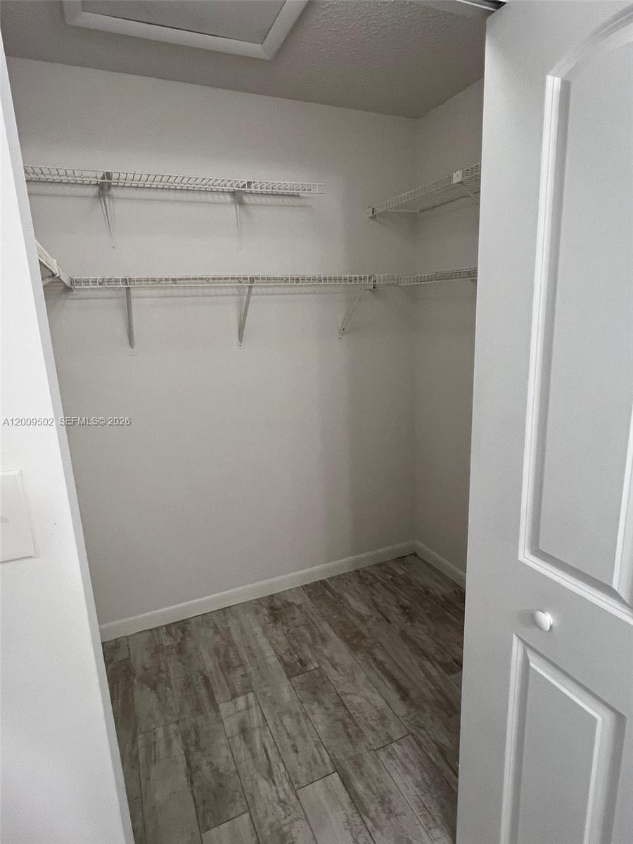 A walk-in closet features white wire shelving and light wood-look flooring — 9203 SW 138th Pl # 9203, Miami FL 33186, MIAMI, FL