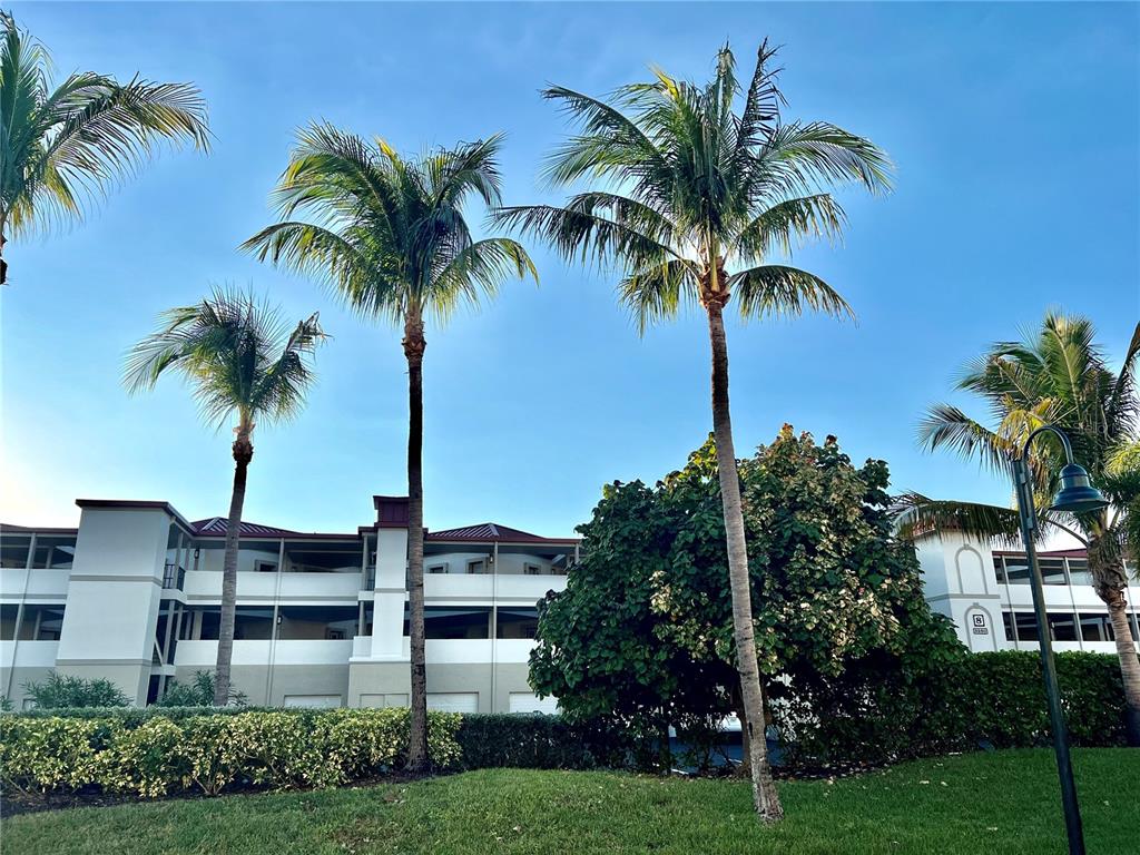 A multi-story building exterior is framed by palm trees and a manicured lawn — 3280 SOUTHSHORE DRIVE UNIT 87A, PUNTA GORDA, FL
