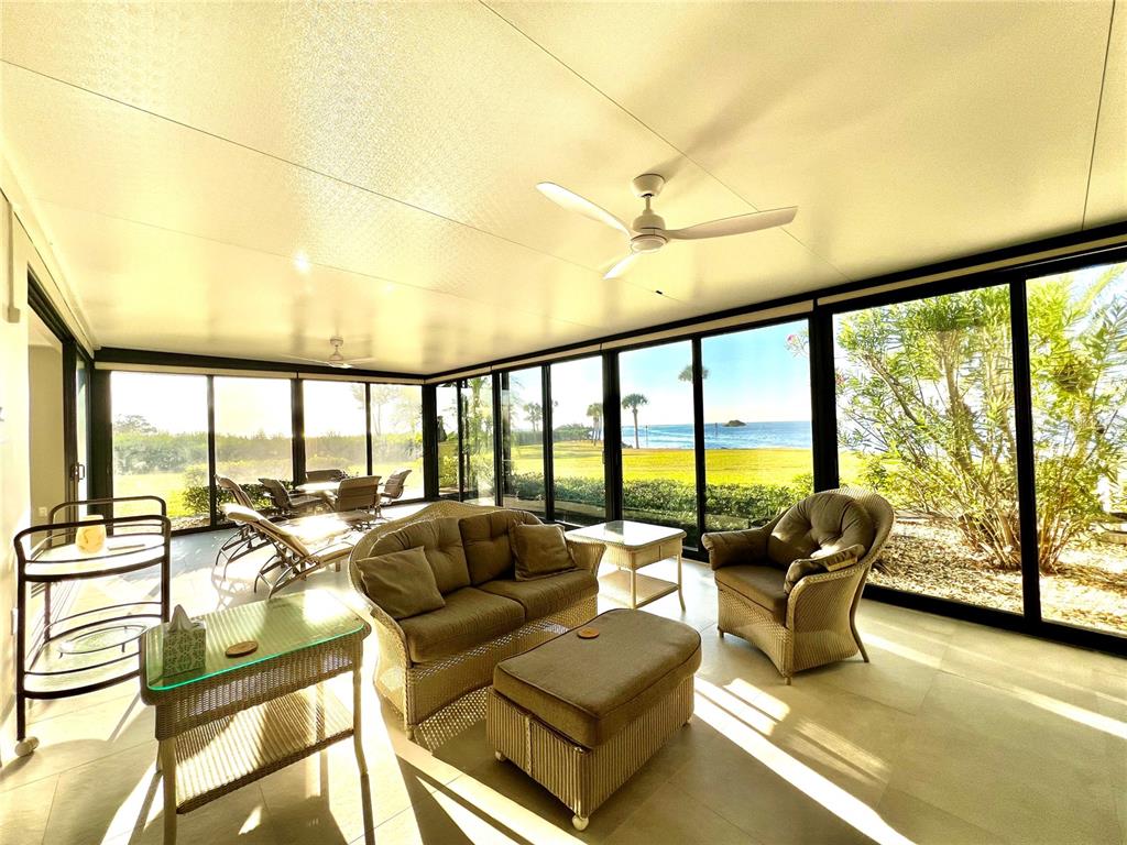 A sunroom with wicker furniture, a ceiling fan, and large windows overlooking the ocean — 3280 SOUTHSHORE DRIVE UNIT 87A, PUNTA GORDA, FL