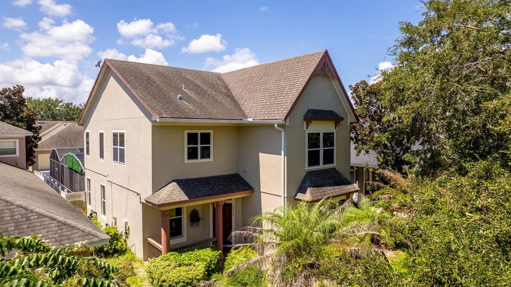 A two-story tan house with a brown shingled roof and a front porch — 12912 DROXFORD ROAD, WINDERMERE, FL