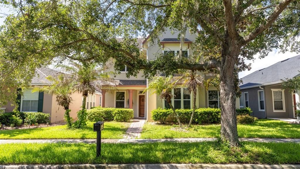 A two-story suburban house with a brick walkway, palm trees, and a large oak tree — 12912 DROXFORD ROAD, WINDERMERE, FL