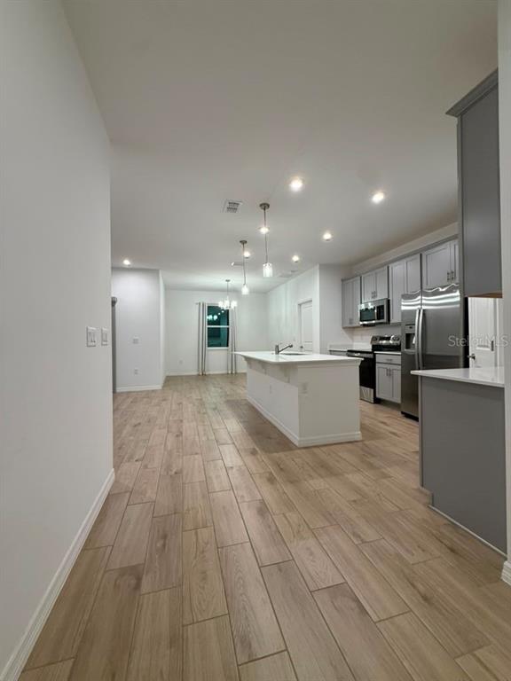 A kitchen with a white island, gray cabinets, and light wood-look tile flooring — 6518 WATERLILY PLACE, LAKE HAMILTON, FL