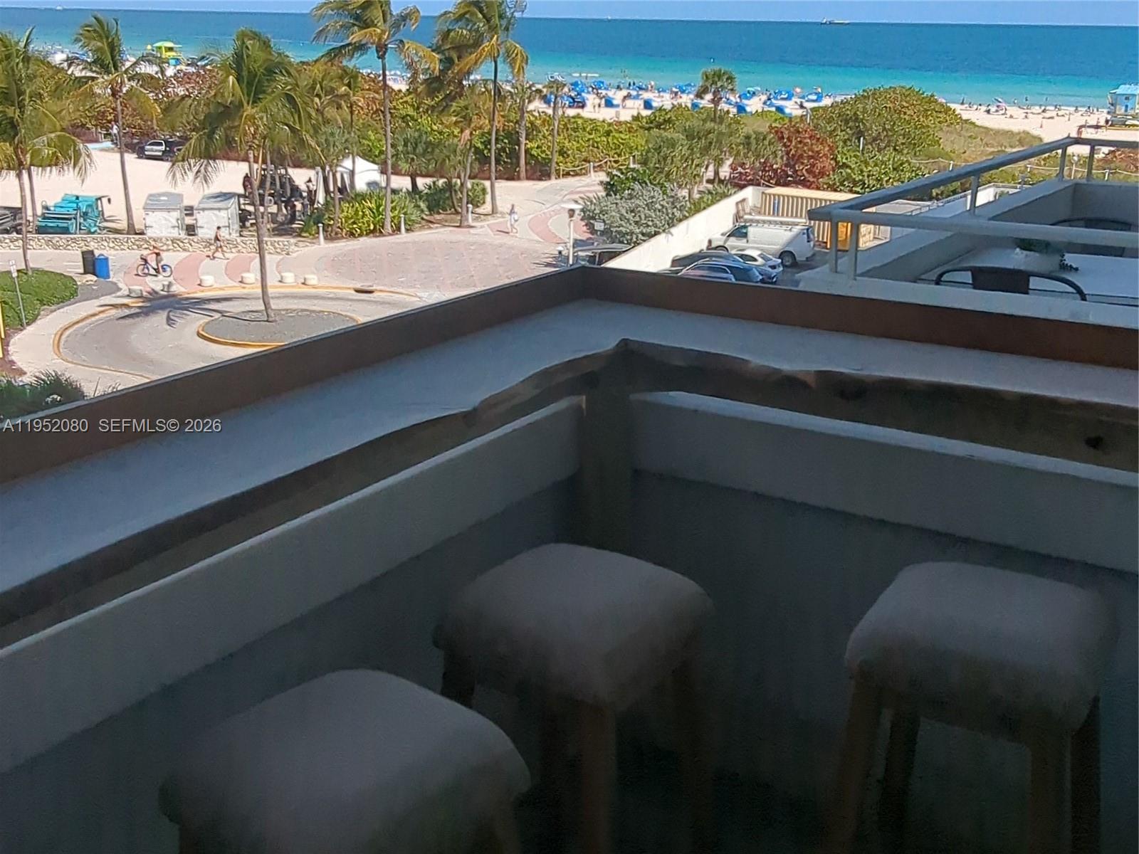 A balcony features a wooden bar top, three stools, and a view of the beach — 465 Ocean Dr # 524, Miami Beach FL 33139, MIAMI BEACH, FL