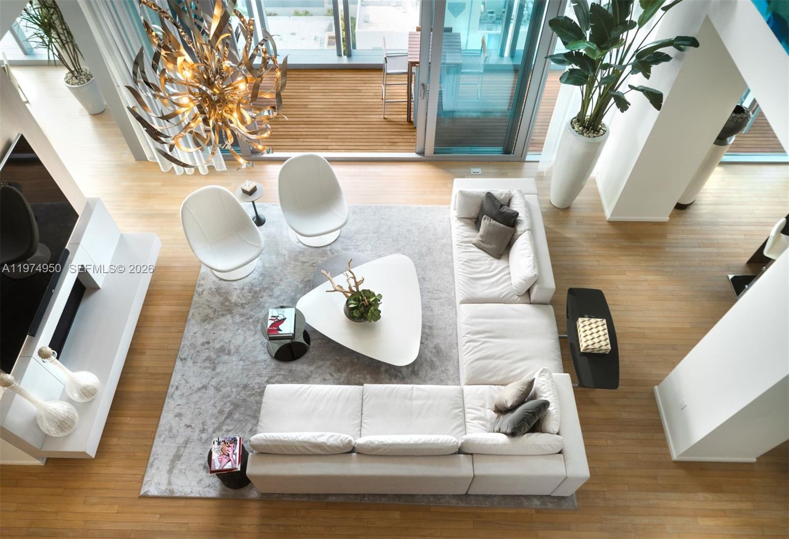 A high-angle view shows a modern living room with a white sectional, triangular coffee table, and chandelier — 2901 E Collins Ave # 1602, Miami Beach FL 33140, MIAMI BEACH, FL