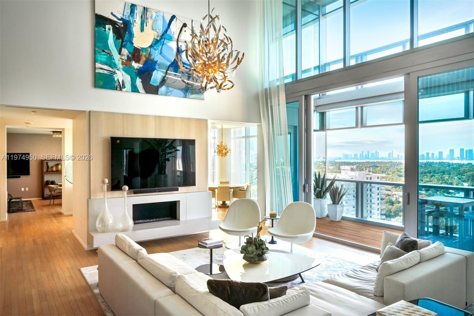A modern living room features a large abstract painting, a fireplace, and floor-to-ceiling windows — 2901 E Collins Ave # 1602, Miami Beach FL 33140, MIAMI BEACH, FL