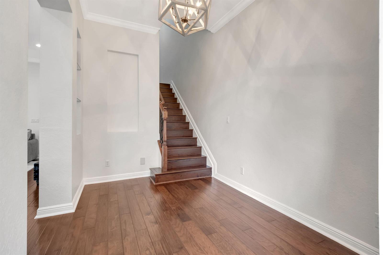 An entryway features hardwood flooring, a wooden staircase, and a geometric chandelier — 8302 NW 8th Terrace # 8302, Boca Raton FL 33487, BOCA RATON, FL