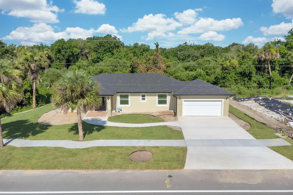 An aerial view of a single-story house with a garage, lawn, and surrounding trees — 4880 BARNA AVENUE, TITUSVILLE, FL