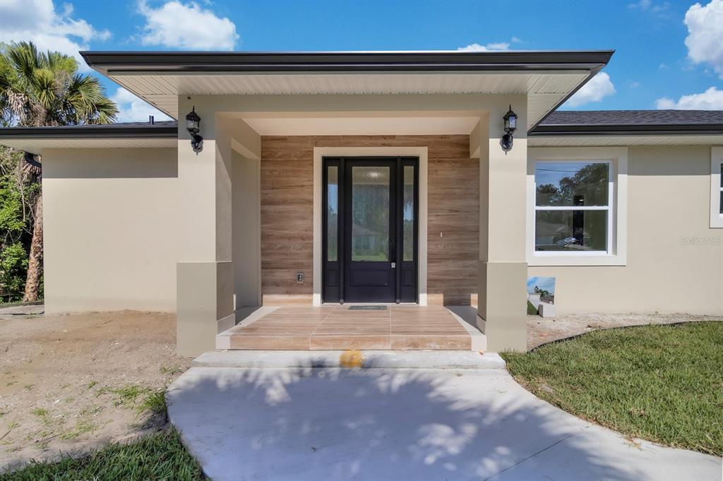 A single-story house with a light-colored exterior, dark roof, and a front-facing garage — 4880 BARNA AVENUE, TITUSVILLE, FL