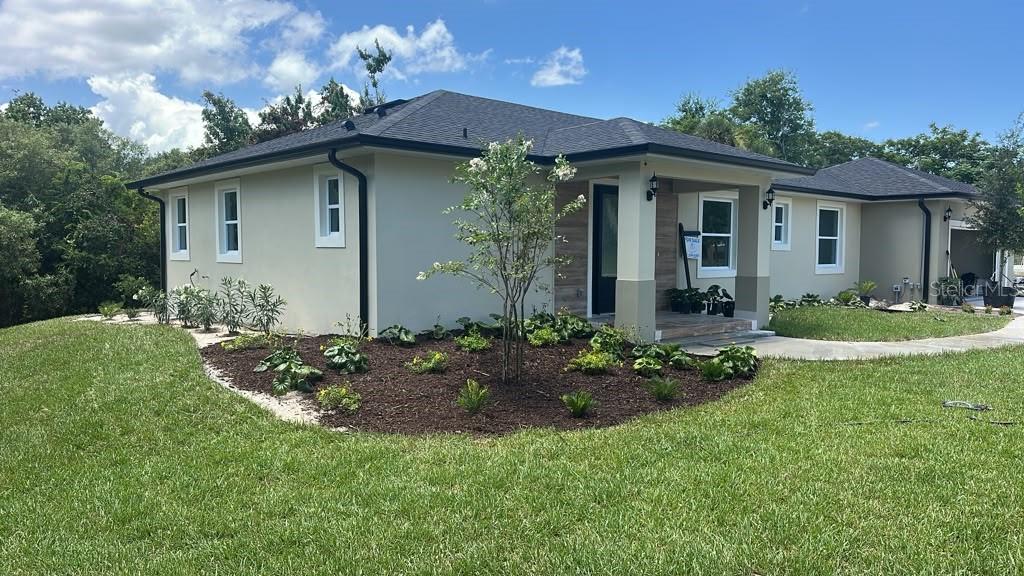 The exterior of a house features a covered entryway with wood-look tile and a dark door — 4880 BARNA AVENUE, TITUSVILLE, FL
