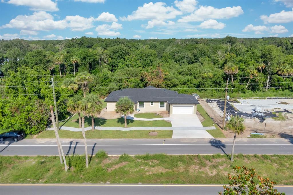 A single-story house with light-colored stucco walls, a dark shingled roof, and landscaped front yard — 4880 BARNA AVENUE, TITUSVILLE, FL