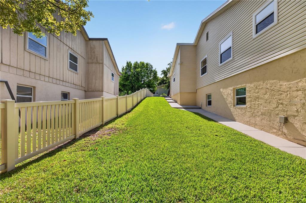 A grassy side yard sits between two houses separated by a tall vinyl fence — 51 SANDPIPER CIRCLE, ORMOND BEACH, FL
