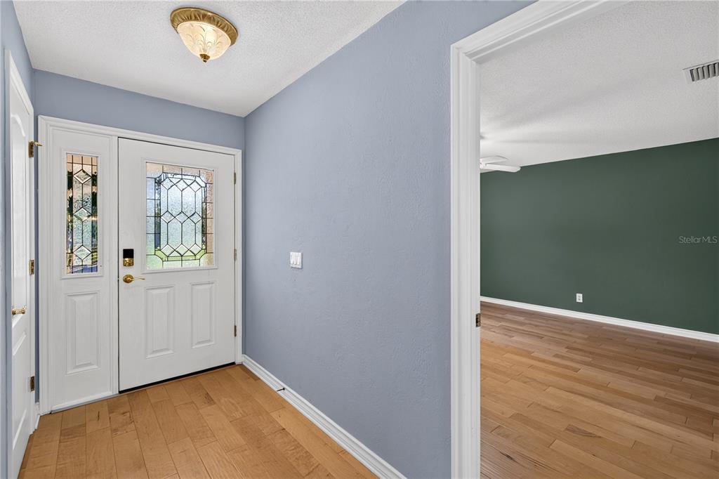 An entryway with light blue walls, wood flooring, and a white door with glass panels — 51 SANDPIPER CIRCLE, ORMOND BEACH, FL