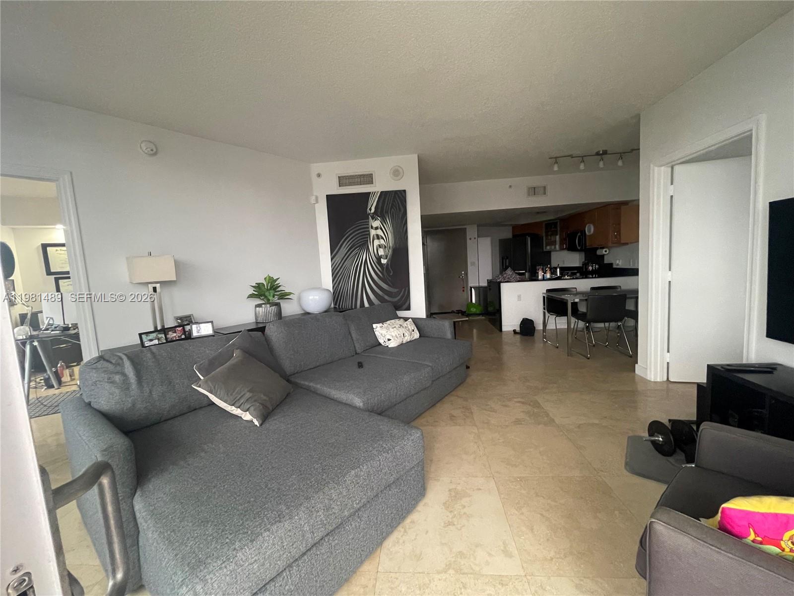 A living room with a gray sectional sofa, tile floors, and an open kitchen area — 1750 N Bayshore Dr # 2814, Miami FL 33132, MIAMI, FL