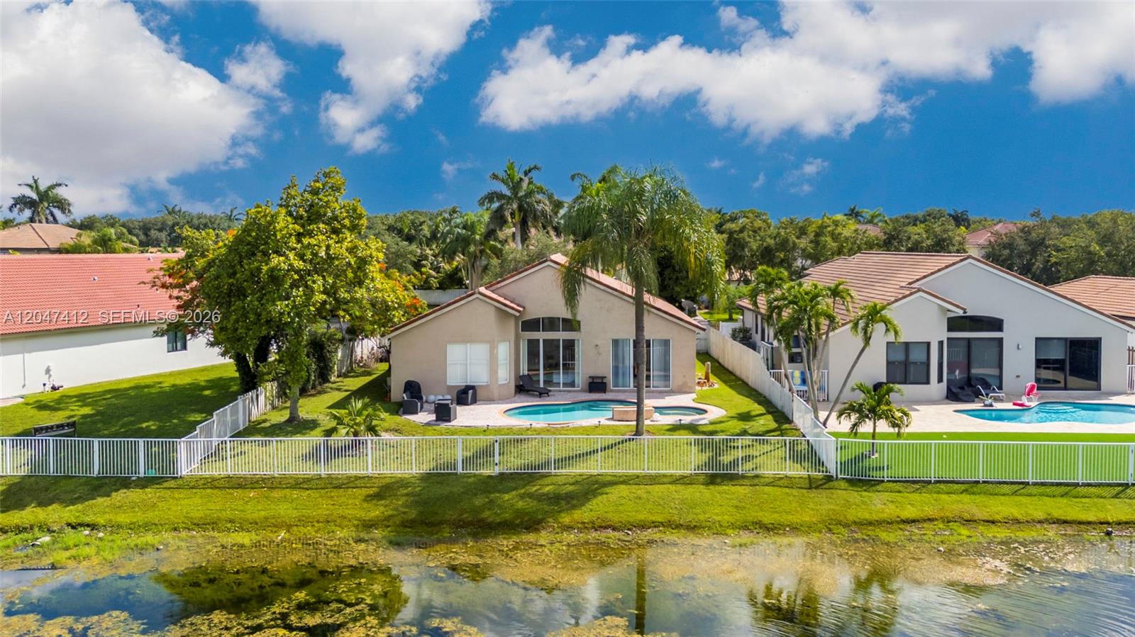 An aerial view shows two suburban houses with swimming pools and backyards facing a pond — 18785 SW 29th St, Miramar FL 33029, MIRAMAR, FL