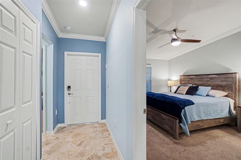 A tiled entryway with a blue wall leads into a bedroom with a wooden bed — 43051 GREENWAY BOULEVARD UNIT 823, PUNTA GORDA, FL